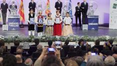 Niños de Huesca ataviados con trajes regionales muestran el número premiado ayer.