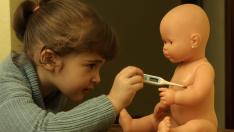 Una niña toma la temperatura a su muñeco.