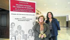 Carmen Teresa Aguelo y Belén Causapé junto al cartel que anuncia la exposición en la Facultad de Derecho