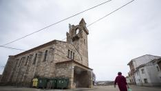 Una vecina cruza delante de la iglesia de Santiago y la torre contigua.