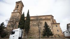 Un camión y un tendero de ropa comparten espacio junto a la imponente parroquia del Salvador en Tornos.