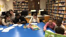 Niños de Fonz enseñan castellano a vecinos inmigrantes en la Biblioteca Municipal