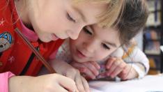 Dos niños hacen juntos los deberes.