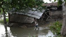 Un hombre camina cerca de su casa, afectada por las inundaciones, en la región de Assam (India).