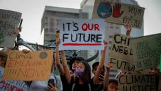 Varias personas sostienen pancartas con mensajes como "Este es nuestro futuro" durante una manifestación contra la crisis climática, este viernes a las afueras de un parque en Bangkok