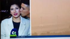 Momento en el que la periodista un besada por un viandante mientras hace un directo sobre la situación del aeropuerto de Lanzarote por la calima