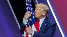 El presidente Trump besa la bandera de EE. UU. durante el acto conservador del sábado.