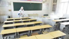 Worker in protective suit sprays disinfectant inside a classroom of a primary school, as students’ return has been delayed due to the novel coronavirus outbreak, in Donghai county of Lianyungang, Jiangsu