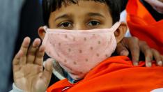 A boy wears a mask as he waits for the start of the first One-day International cricket match between India and South Africa, amid coronavirus fears, in Dharamsala