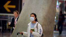 A passenger, wearing a protective mask, walks to check-in for her flight to the U.S. at Madrid's Adolfo Suarez Barajas Airport