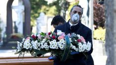 Un trabajador de una funeraria transporta una corona de flores en un cementerio de Bérgamo, en Italia.