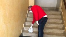 Un voluntario deposita una bolsa de medicamentos en las escaleras de acceso a una vivienda