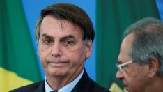Brazil's President Jair Bolsonaro reacts near Brazil's Economy Minister Paulo Guedes during a media statement announcing economic measures, amid coronavirus disease (COVID-19) outbreak, in Brasilia