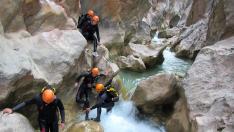 Un guía ayuda a un grupo de barranquistas en la Sierra de Guara a atravesar un paso complicado.