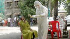 A health-worker wearing personal protective equipment (PPE) collects a sample using a swab from a woman during a check-up campaign for the coronavirus disease (COVID-19), at a residential society in Mumbai