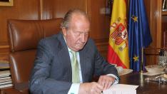 Don Juan Carlos, en 2014, en el momento de firmar el documento de su abdicación.