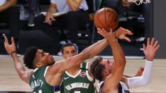 Antetokounmpo trata de bloquear una entrada de Doncic.