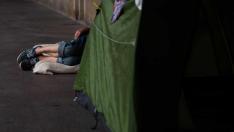 Una persona sin hogar descansa en un colchón en los porches de los antiguos juzgados de la plaza del Pilar.