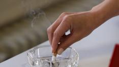 Una fumadora apagando un cigarrillo en un cenicero