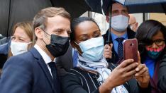 French President Emmanuel Macron poses for a selfie with a resident during a visit in Les Mureaux