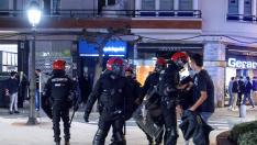 Miembros de la Ertzaintza detienen a un joven tras las protestas que se han producido esta noche en las calles de Bilbao, por las medidas impuestas ante el aumento de contagios de Coronavirus.