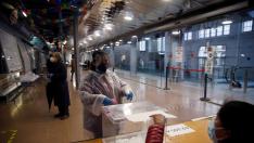 Una mujer protegida con un traje vota en el colegio electoral situado en el Mercat del Ninot en Barcelona.