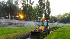 Una excavadora retira restos de vegetación y de gravas del caucel del Isuela a su paso por Huesca.
