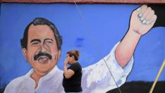 Una mujer pasa por un muro en el que está pintado Ortega.