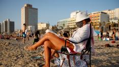 Una mujer con mascarilla en una playa cercana a Tel Aviv