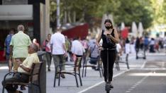 Una chica mira el móvil mientras circula en patinete este jueves en Zaragoza.