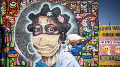 Una mujer pasa por delante de un mural que recuerda la pandemia en Johanesburgo