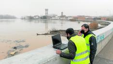 Dos técnicos de la CHE siguen la crecida en Cabañas y analizan en el ordenador modelizaciones del comportamiento del río.