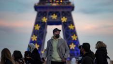 Varias personas delante de la Torre Eiffel de París, que tiene estos días una iluminación dedicada a la Unión Europea FRANCE COVID19 PANDEMIC