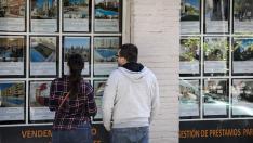Dos jóvenes, observando ofertas en una inmobiliaria.