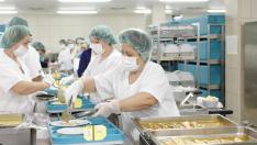 Profesionales del Servicio de Hostelería emplatan la comida en la cocina del Hospital Miguel Servet de capital aragonesa.