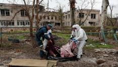 Cuatro personas trasladan un cadáver en Mariúpol