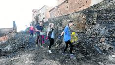 Un grupo de jóvenes limpian la zona quemada en Moros, que llegó a las puertas de los locales de las peñas.