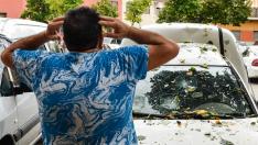 Un hombre mira los daños en un vehículo por la granizada en La Bisbal d'Empordá