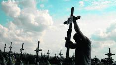 Un voluntario coloca el pasado agosto un cruz con un número en una tumba anónima entre enterramientos de asesinados por tropas rusas en Bucha.