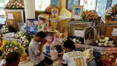 Varias personas rezan ante los féretros de algunos niños asesinados en la guardería tailandesa.