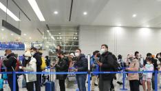 Pasajeros hacen fila para pasar por los controles de entrada en el Aeropuerto Internacional de Shanghai, este domingo.
