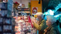 Personas mayores conversan con un detallista del Mercado Central de Zaragoza.