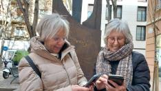 Marisa Gracia y Teresa Mainar, con sus teléfonos móviles en el centro de Zaragoza.