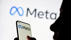 FILE PHOTO: Woman holds smartphone with Meta logo in front of a displayed Facebook's new rebrand logo Meta in this illustration picture