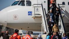 Un grupo de refugiados sirios provenientes de Turquía y afectados por el terremoto bajan del avión en la base aérea de Torrejón de Ardoz