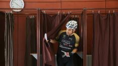 Un ciclista sale de una cabina con las papeletas preparadas para ejercer su derecho al voto de salir a hacer deporte, en el colegio Rosales del Canal de Zaragoza