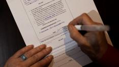 Imagen de archivo de una mujer firmando la solicitud de la prestación de ayuda para morir en su casa.