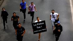 Un joven corre junto a otros mientras sostiene una pancarta que dice 'La policía mata', tras la muerte de un joven en Nanterre, Francia.