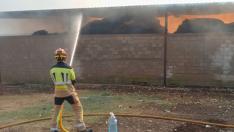 Un bombero apaga el fuego declarado en un almacén de paja en La Ginebrosa.