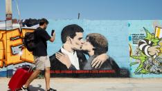 Un hombre hace una foto en Barcelona a un grafiti en el que aparecen Sánchez y Puigdemont besándose